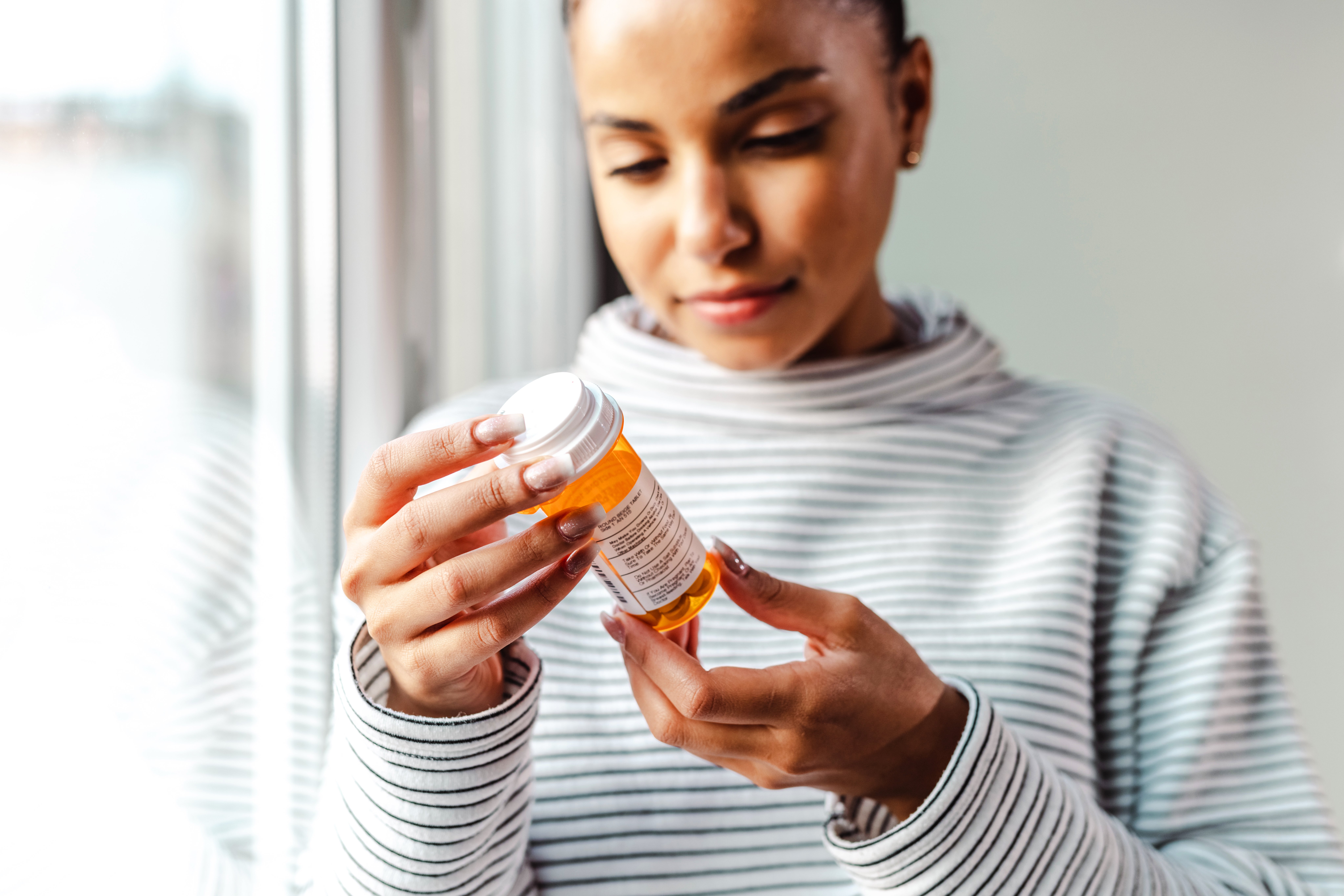 GettyImages-1450420379-Woman_Looking_at_Pills-RET-1
