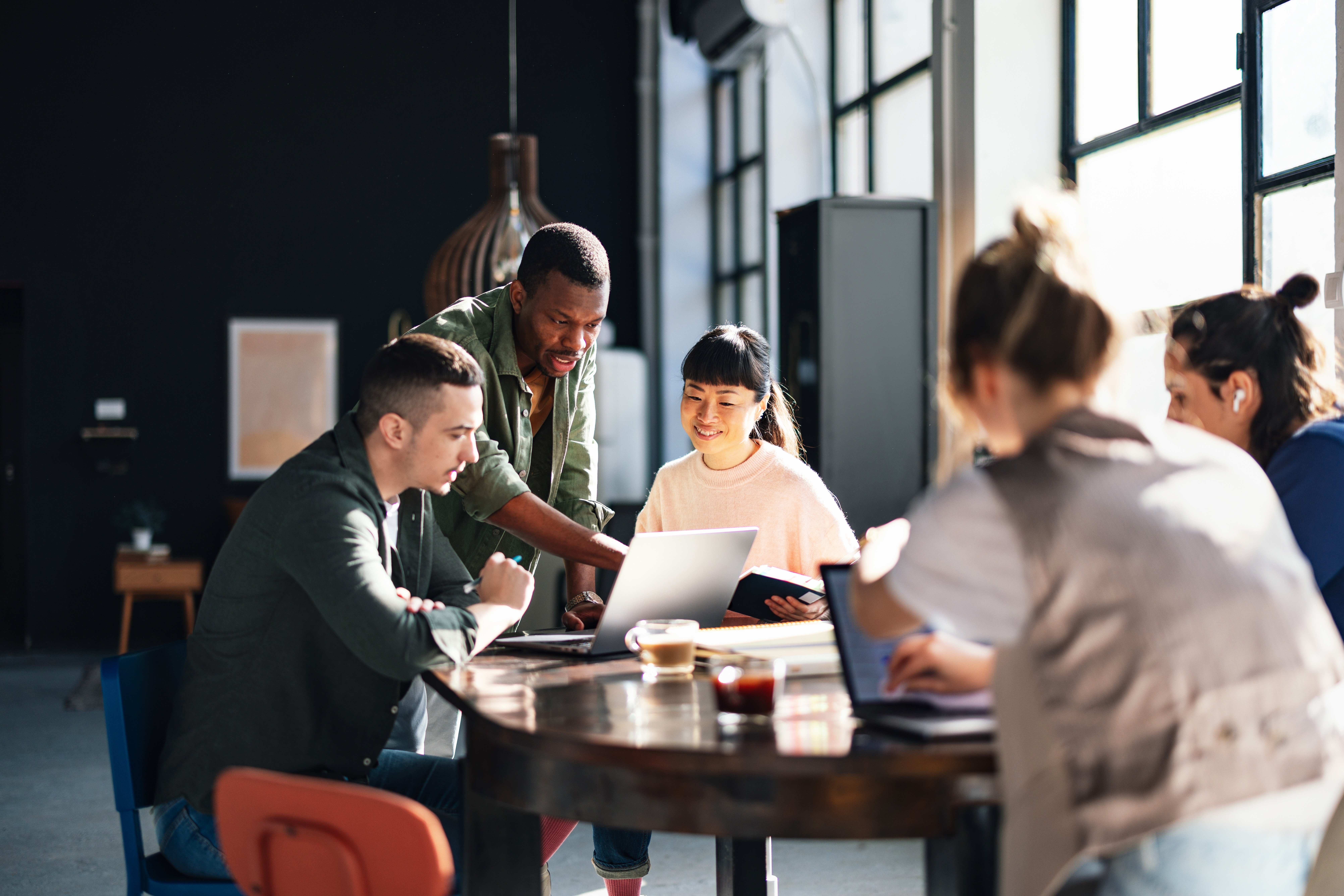 Young professionals or students collaborating in a bright, contemporary co-working environment, displaying teamwork and productivity.
