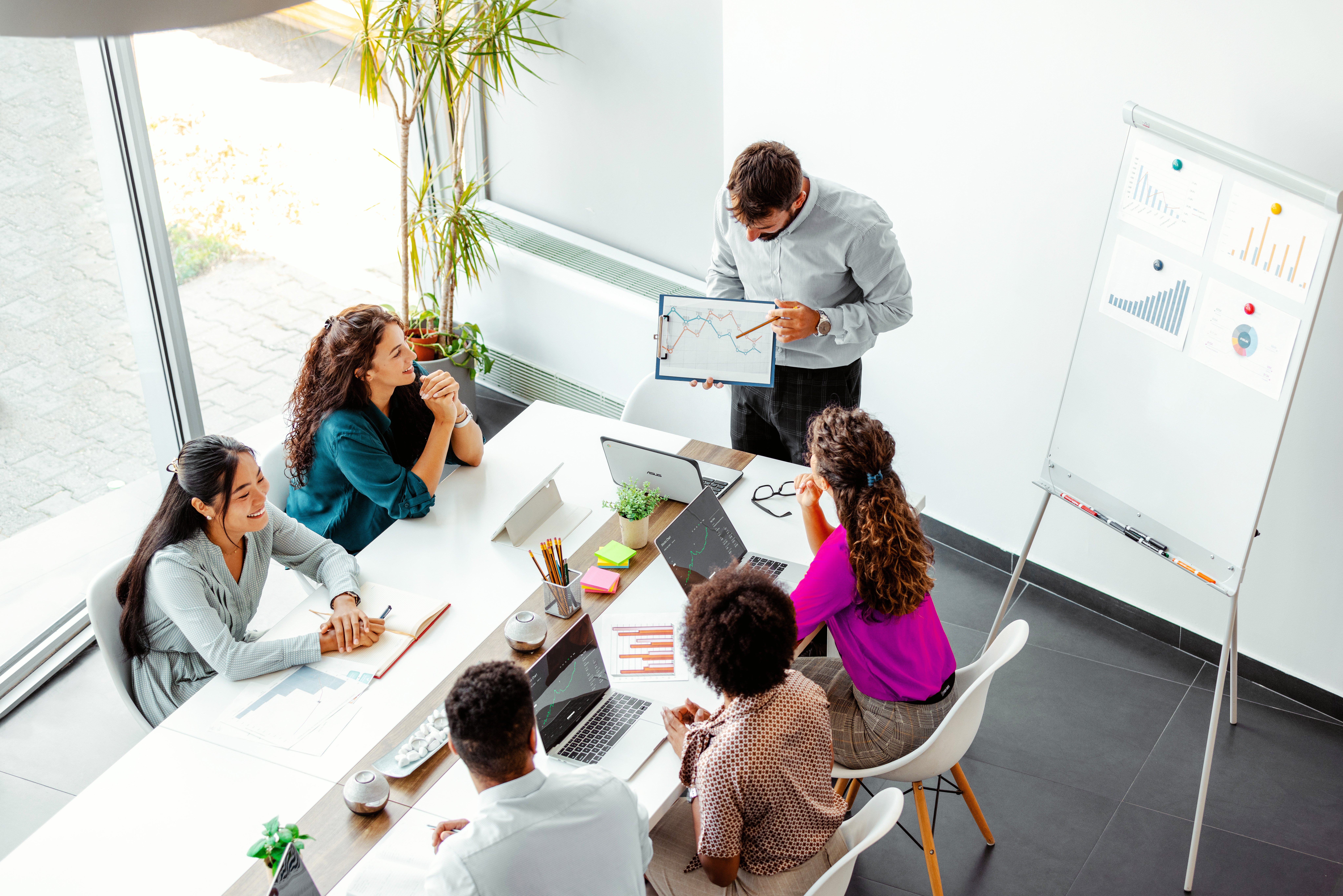 Corporate businessman points to charts in business meeting with colleagues.