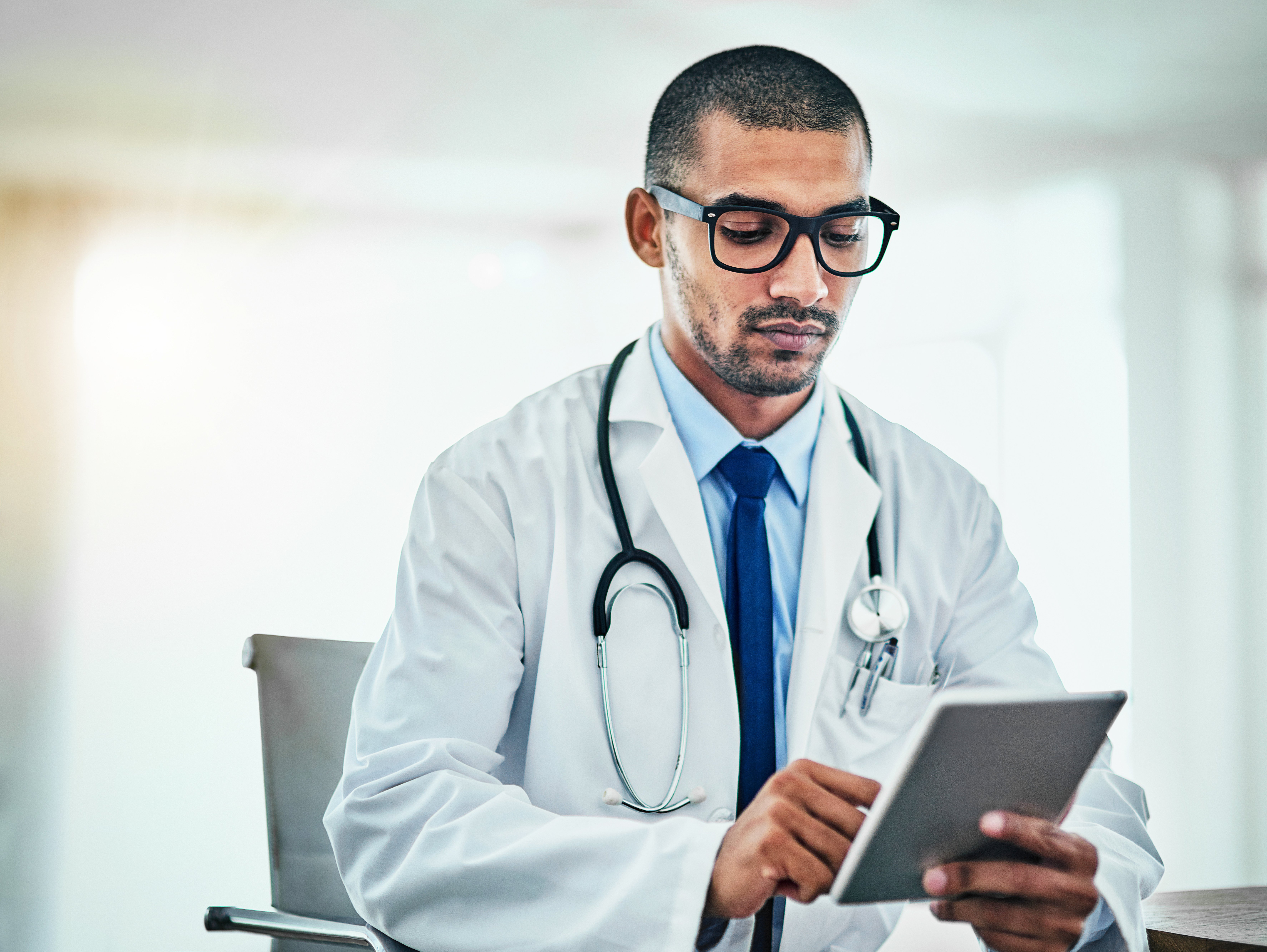 Cropped shot of a young male doctor working on a digital tablet in his office